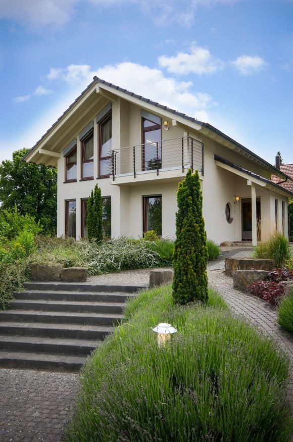Blick auf Haus mit gepflegtem Vorgarten, erreichbar über eine Treppe und gepflasterten Weg